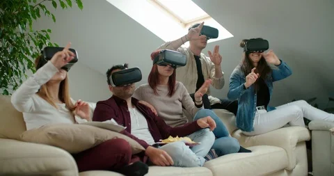 Group of friends using virtual reality simulator glasses in living room. Shot in Stock Footage 118066234