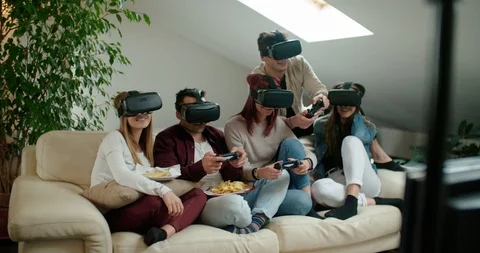 Group of friends using virtual reality simulator glasses in living room. Shot in Stock Footage 118067052