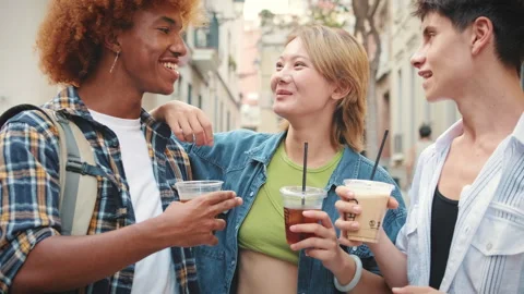 Group of friends walking with takeout drinks along city street, chatting and Stock Footage 250843434