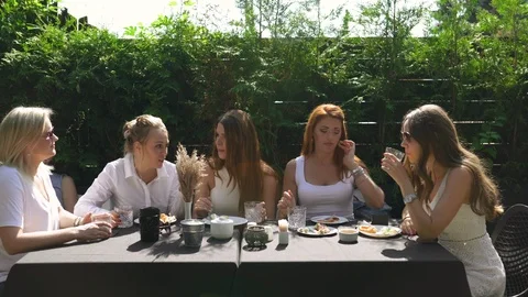 Group of friends in white having breakfast in garden at table with food and Stock-Footage 114317643