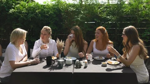 Group of friends in white having breakfast in garden at table with food and Stock-Footage 114317710