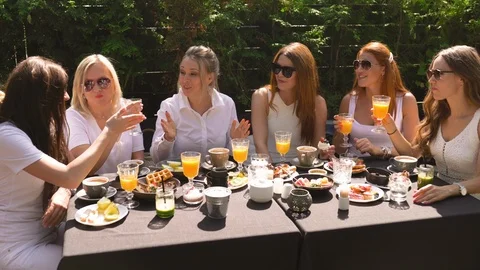 Group of friends in white having breakfast in garden at table with food and Stock-Footage 114317834