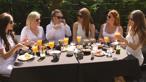 Group of friends in white having breakfast and toasting with yellow orange juice Stock-Footage 114317860