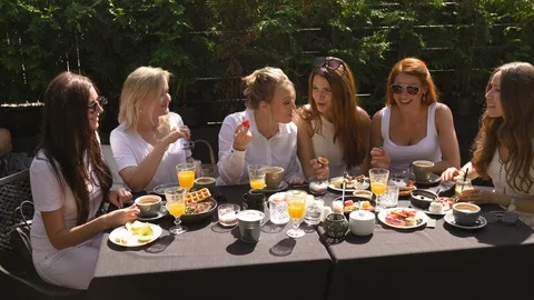 Group of friends in white having breakfast in garden at table with food and Stock-Footage 114318017