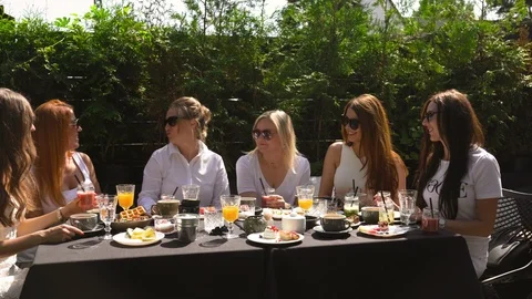 Group of friends in white having breakfast in garden at table with food and Stock-Footage 114318330