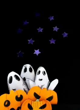 Group of ghosts playing at scaring, coming out from behind pumpkins. Stock Photos
