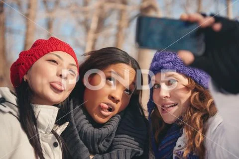 Group of girl friends enjoying taking selfies in the snow in winter Stock Photos