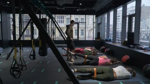 Group of girls doing exercises with trainer instructor raising legs lying on the Vídeo Stock 104966439