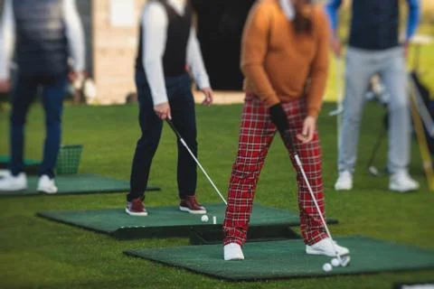 Group of golfers practicing and training golf swing on driving range practice Stock Photos