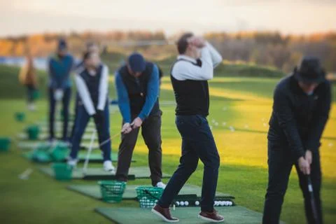 Group of golfers practicing and training golf swing on driving range practice Stock Photos