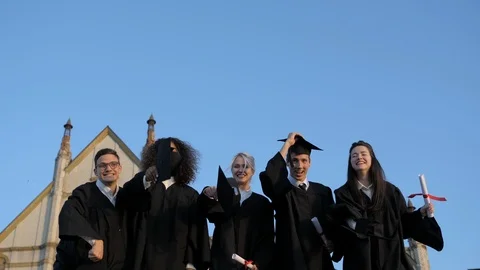 Group of graduates throwing their caps up in the air happily. Vídeo Stock 117089361