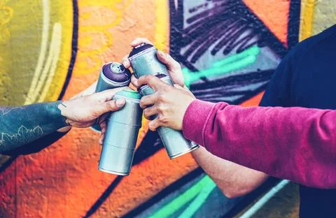 Group of graffiti artists stacking hands while holding spray color can Stock Photos