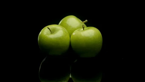 A group of green apples rotating on a black background Stock Footage