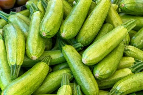 A group of green courgettes for sale at an outdoor market. Stock Photos