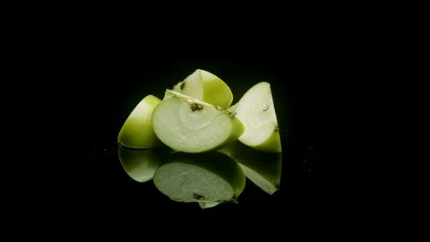 A group of green sliced apples rotating on a black background Stock Footage 128722117