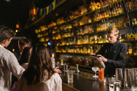 Group of guests supervises professional work of bartender Stock Photos