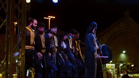 A group of guys dancing Palestinian dabka on stage with a lead dancer to Stock Footage 146049038