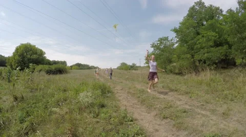 Group of happy children running down the hill in a meadow and roll the wheel. 库存影片 53526568
