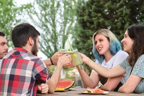 Group of happy friends toasting, having fun, drinking and eating fruit Stock Photos