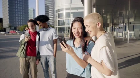 Group of happy friends using the mobile in the street. Young smiling people Stock Footage 231254635