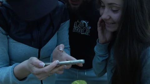 A group of happy friends is viewing photos on the smartphone. Beautiful people Stock Footage