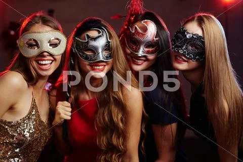 Group of happy girls in masquerade masks having party Stock Photos