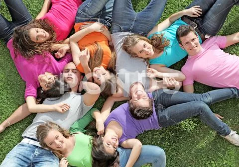 Group of happy healthy kids laying outdoors on grass at summer camp Stock Photos