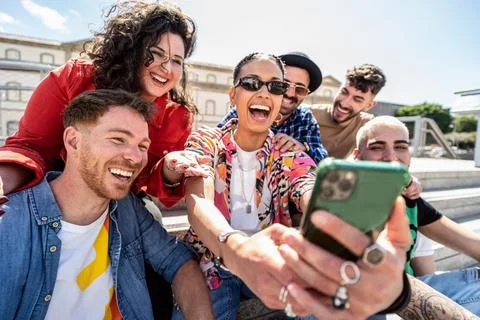 Group of happy multiracial friends using smartphone outdoors Stock Photos