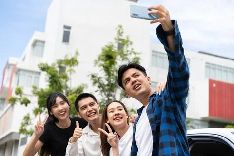 Group of happy young Asian students selfies and videos with smartphones tog.. Stock Photos