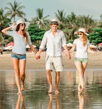Group of happy young people walking along the beach on beautiful summer sunset Stock Photos