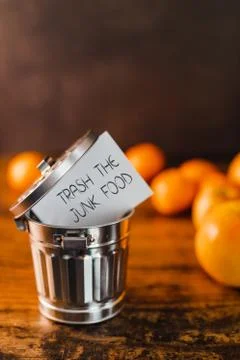 Group of healthy fruit next to Junk food message going into the trash Stock Photos