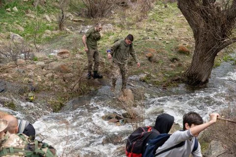 Group of hikers navigating a shallow mountain stream. 스톡 사진