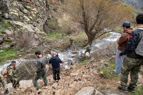 Group of hikers navigating a shallow mountain stream. Stock Photos