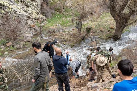 Group of hikers navigating a shallow mountain stream. 스톡 사진