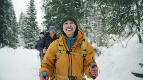 Group hiking through snowy forest with smiling woman leading the way on winter Stock Footage 341337635