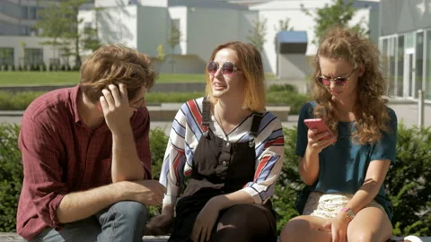 Group of hipsters having a conversation while using mobile phones. Stock Footage 132545185
