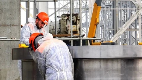 Group of hired labor in red helmets sharpen detail with special tools Stock Footage 74110826