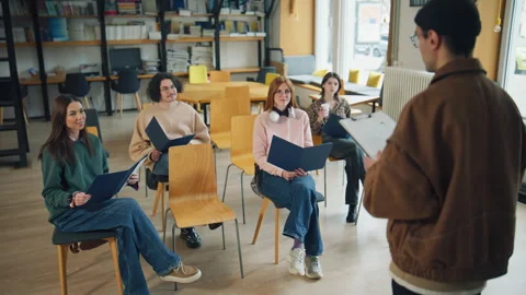 Group of individuals in a library attending a discussion with one person standin Vidéo 337105489