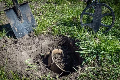 A group of individuals is searching for artifacts using a metal detector in a Stock Photos