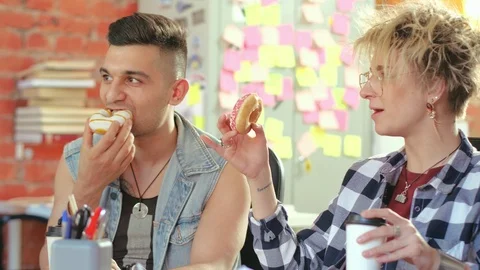 Group it programmers drinking coffee and eating donuts during break in office Video stock 93171083