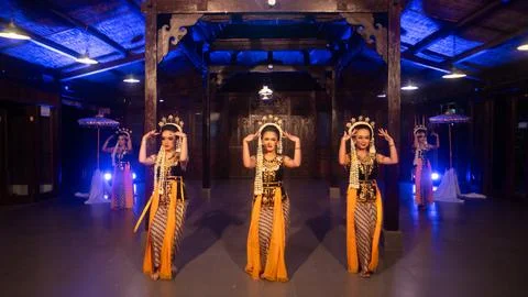 A group of Javanese dancers in traditional patterned costumes dance with th.. Stock Photos