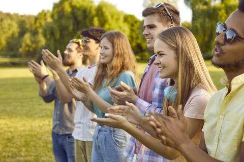 Group of joyful contented multiracial young people applaud and cheer together in Stock Photos