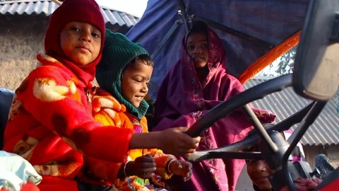 Group of kid playing and having fun over a tractor in rural India Stock Footage 118274585