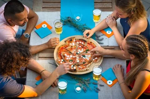 Group of kids eating pizza around the table Stock Photos