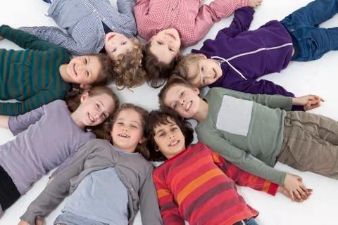 A group of kids lying on their backs in a circle, heads touching Stock Photos