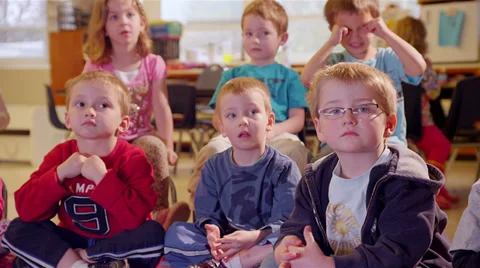 A group of kids sit together in class and listen to someone give show and tell Stock Footage 34005105