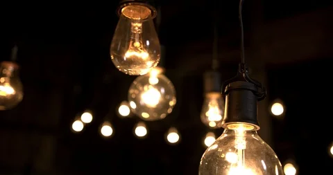 Group of light bulbs stringed up in a dark room Stock Footage 98356981