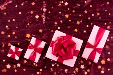 A group of light pastel pink boxes tied with a red satin ribbon with a bow of Stock Photos