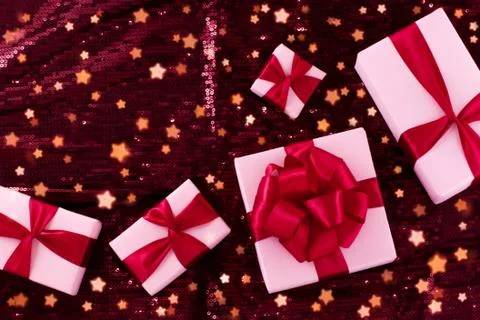 A group of light pastel pink boxes tied with a red satin ribbon with a bow of Stock Photos