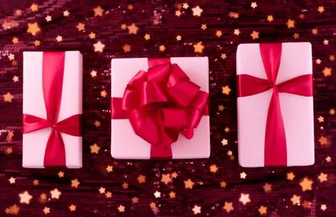 A group of light pastel pink boxes tied with a red satin ribbon with a bow of Stock Photos